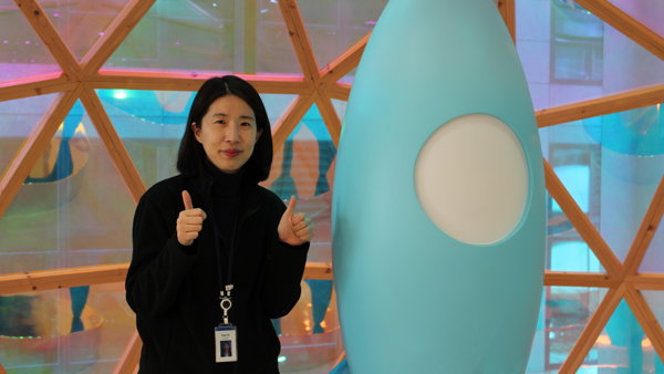 파란 로켓 조각상 옆에 서 있는 사람