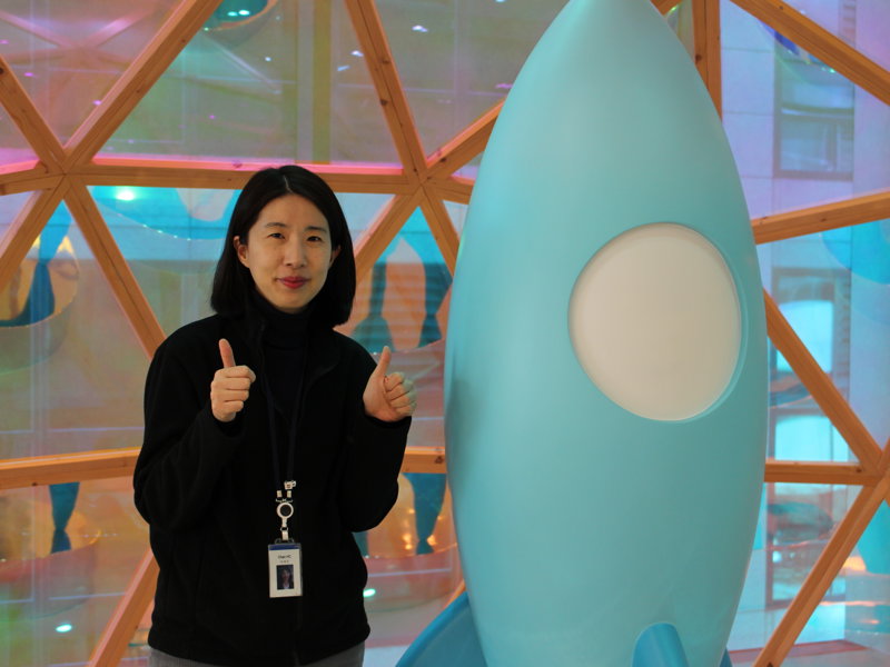 파란 로켓 조각상 옆에 서 있는 사람