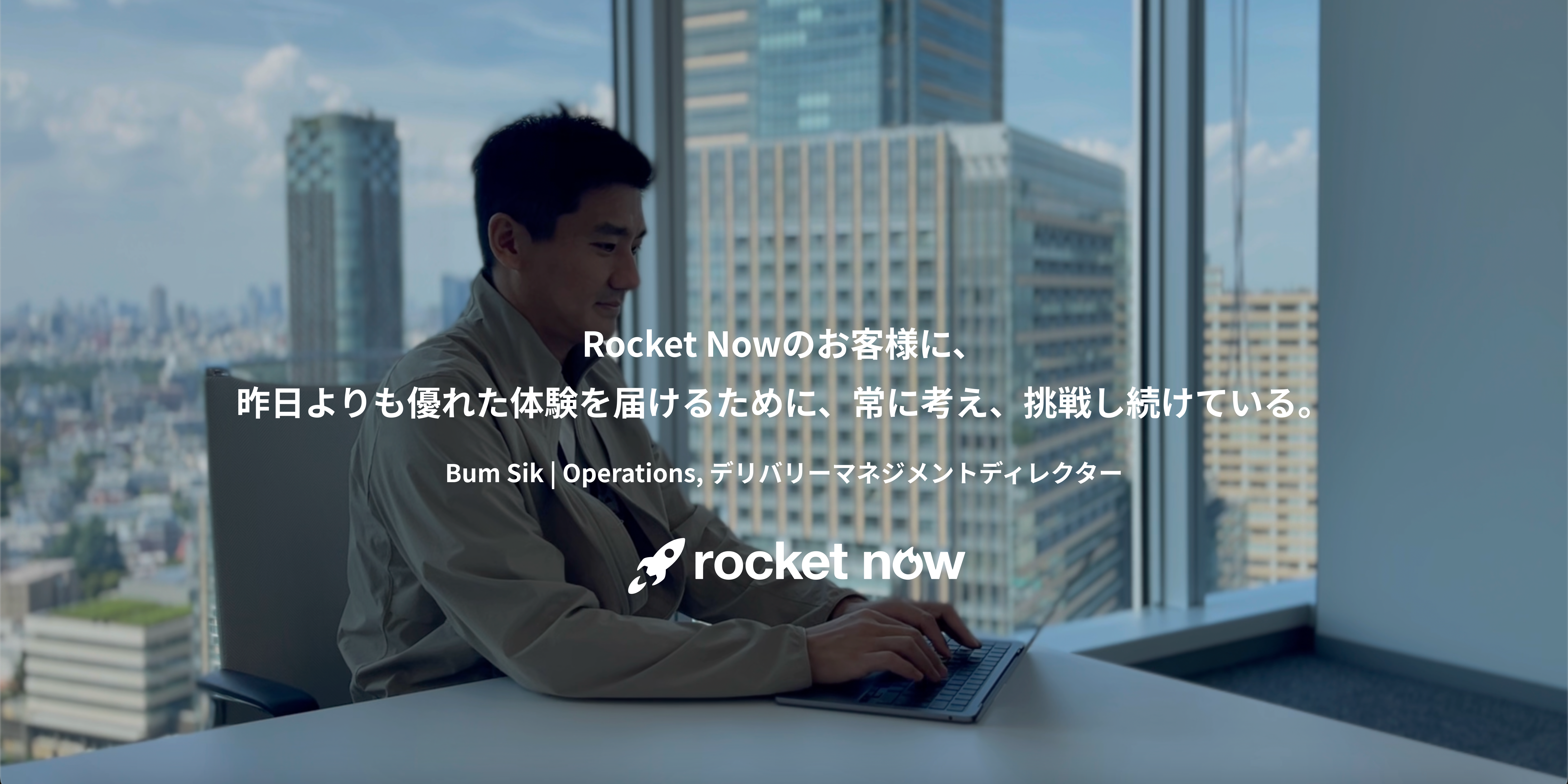 机に座ってノートパソコンを使う人