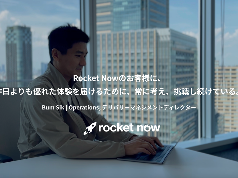机に座ってノートパソコンを使う人