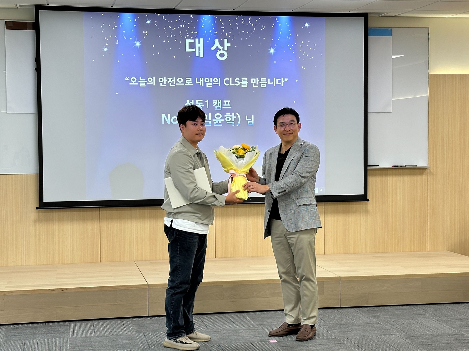 꽃을 들고 스크린 앞에 서 있는 두 남자