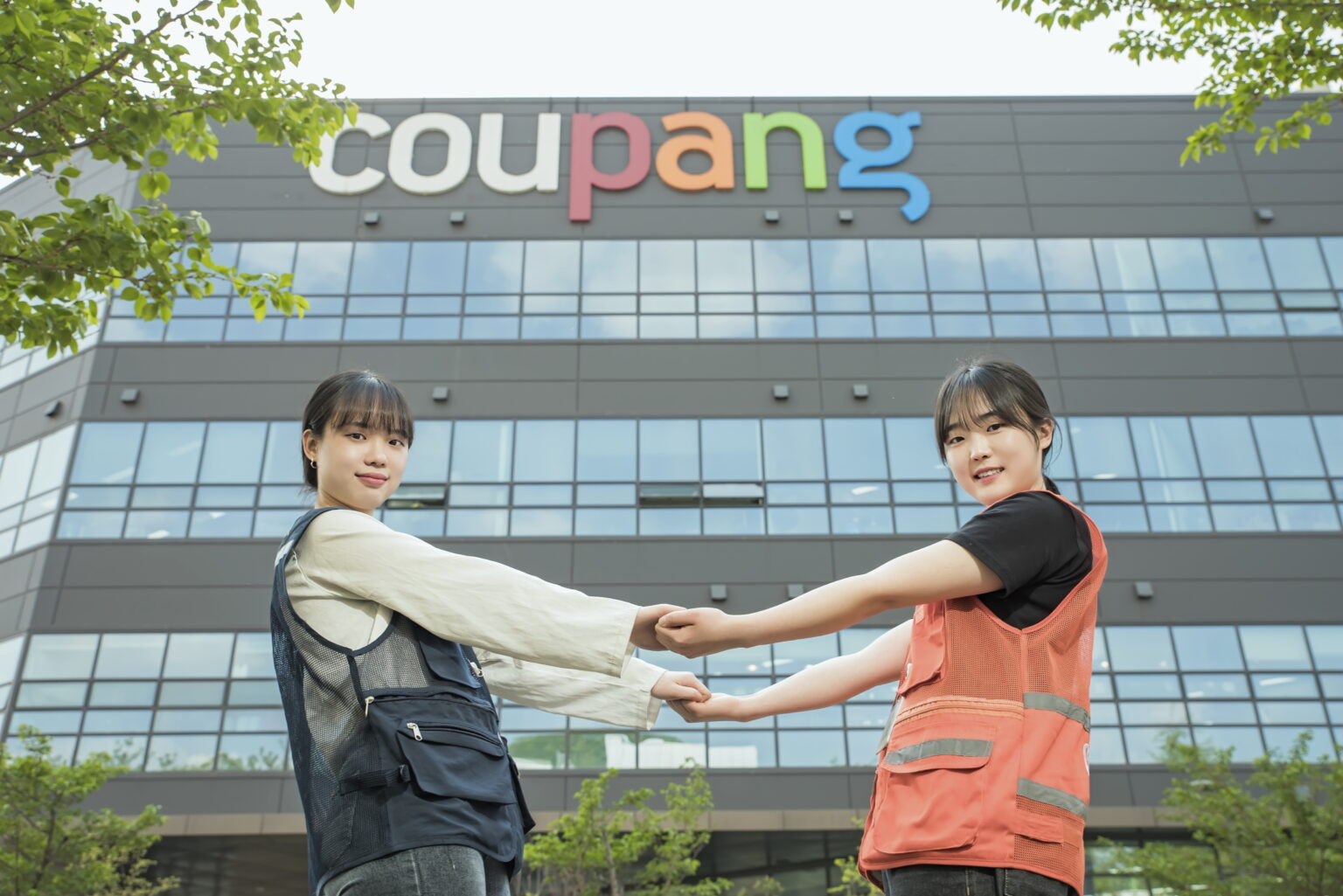 two women holding hands in front of a building
