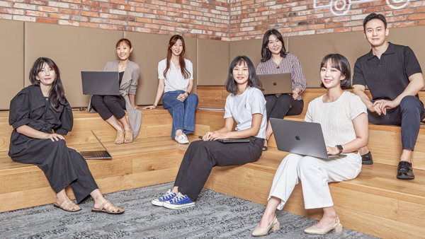 노트북을 들고 나무 계단에 앉아 있는 한 무리의 여성들