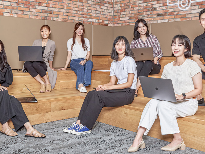 노트북을 들고 나무 계단에 앉아 있는 한 무리의 여성들
