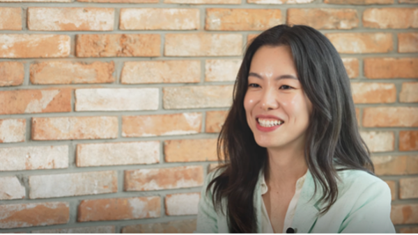 a person smiling in front of a brick wall