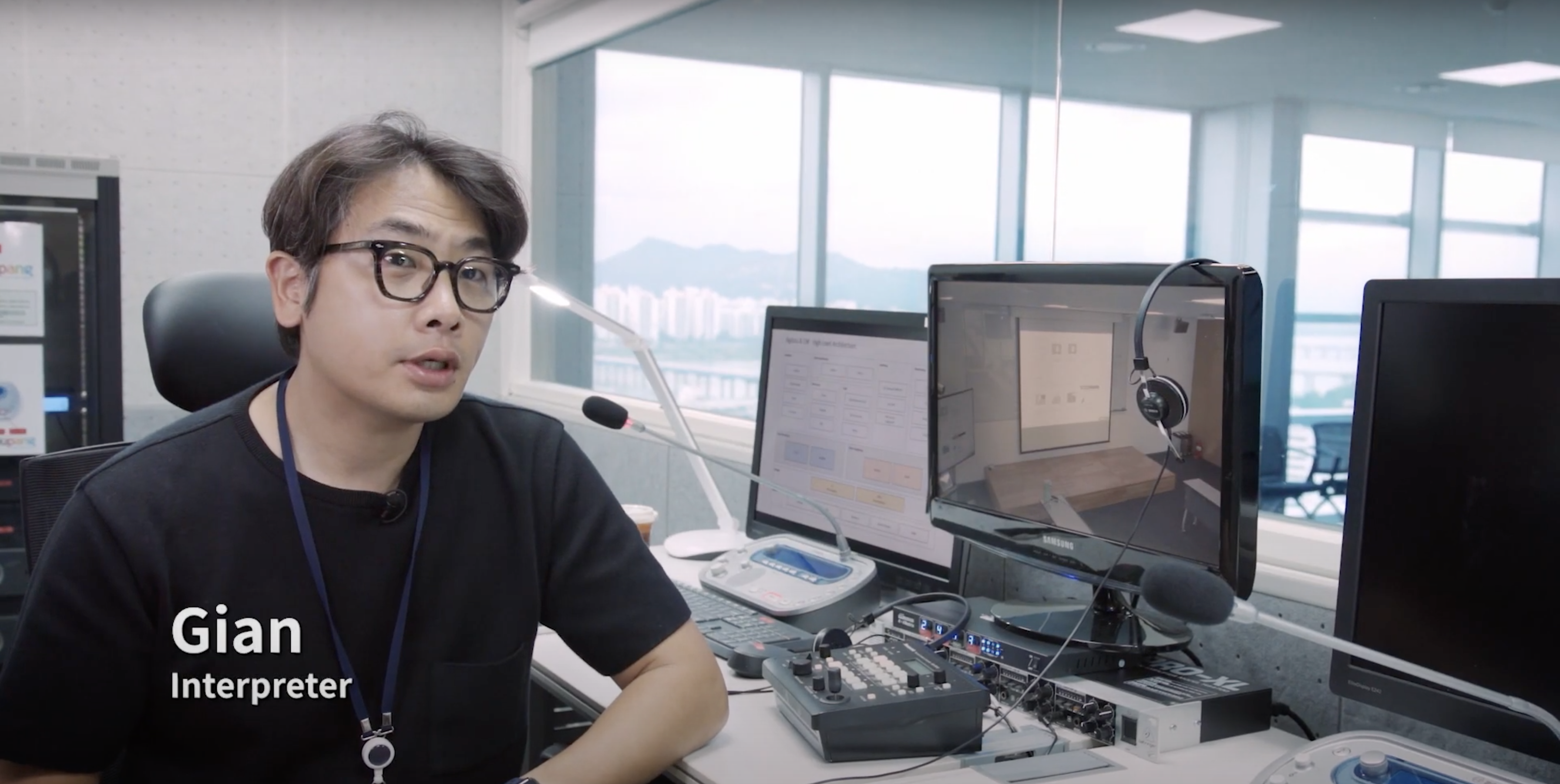 마이크와 컴퓨터 화면이 있는 책상에 앉아 있는 사람