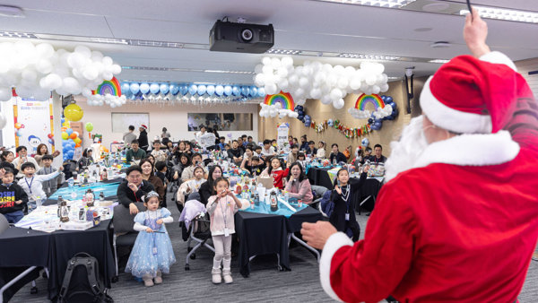 빨간 양복과 흰 모자를 쓴 사람이 한 무리의 사람들 앞에 서 있다