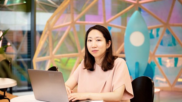 一个人坐在桌子旁,手里拿着一台笔记本电脑