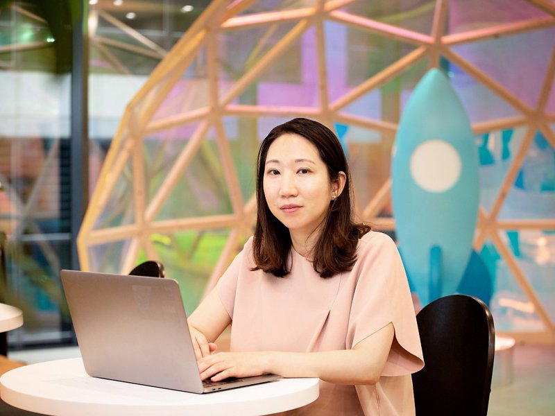 一個人坐在桌子旁,手裡拿著一台筆記型電腦