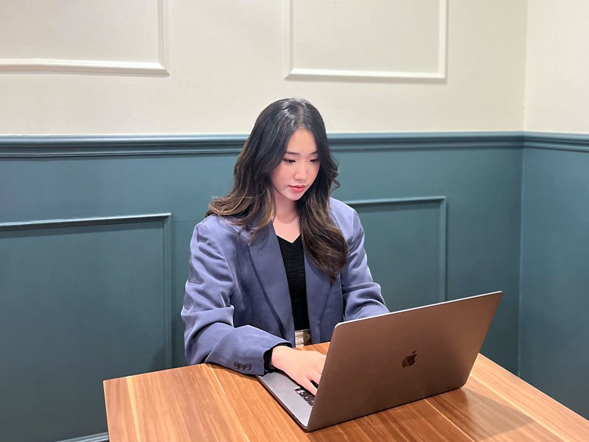 노트북을 들고 책상에 앉아 있는 사람