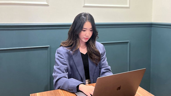 노트북을 들고 책상에 앉아 있는 사람