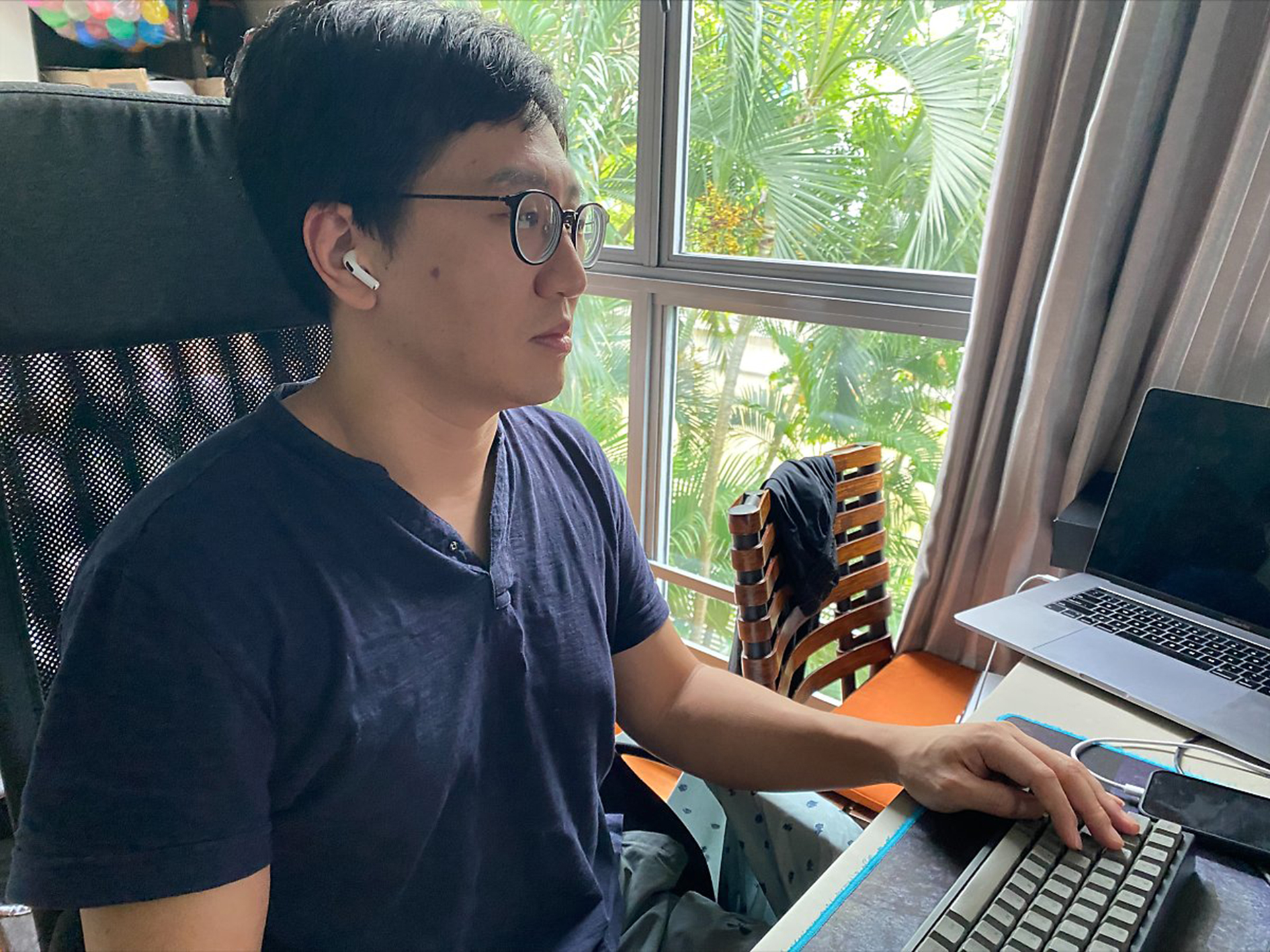 노트북과 창문이 있는 책상에 앉아 있는 사람