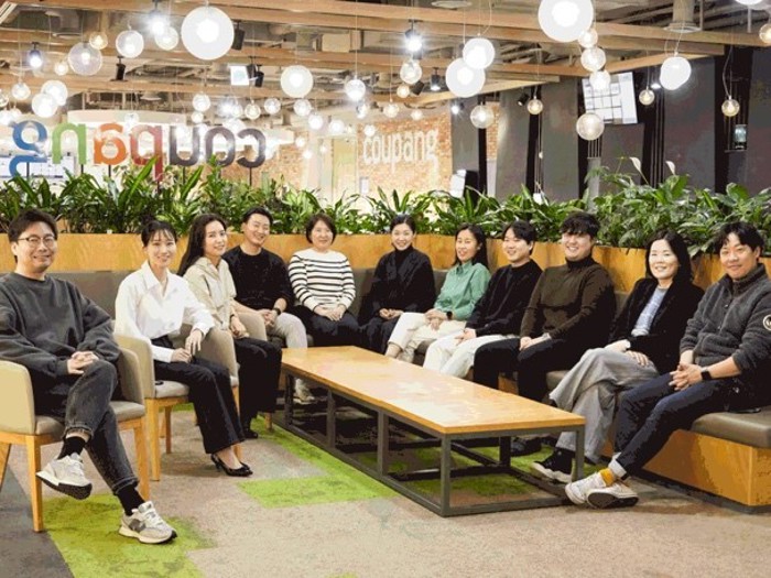a group of people sitting on chairs in a room with plants