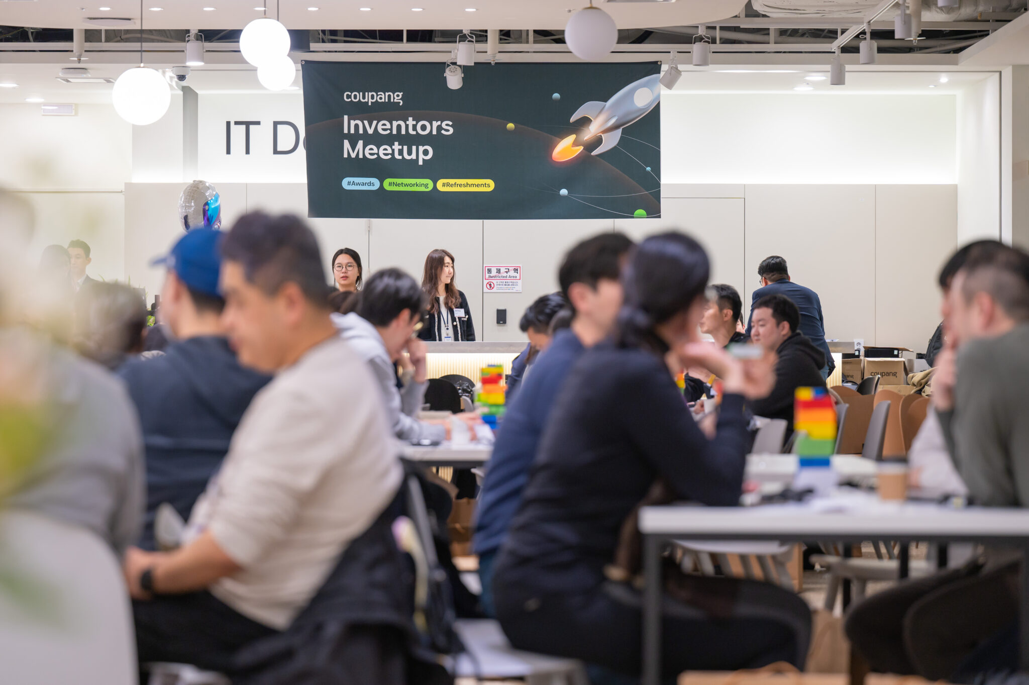 a group of people sitting at tables in a room with a sign