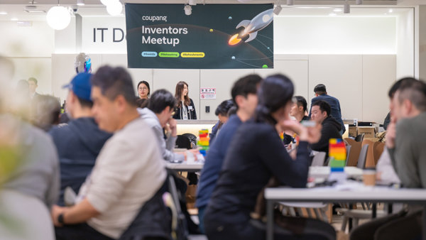 a group of people sitting at tables in a room with a sign