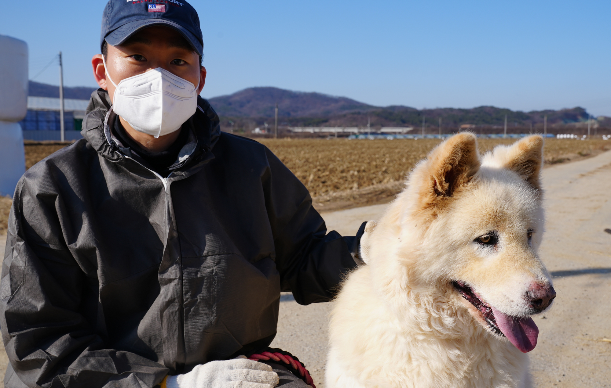 마스크를 착용하고 개를 안고 있는 사람