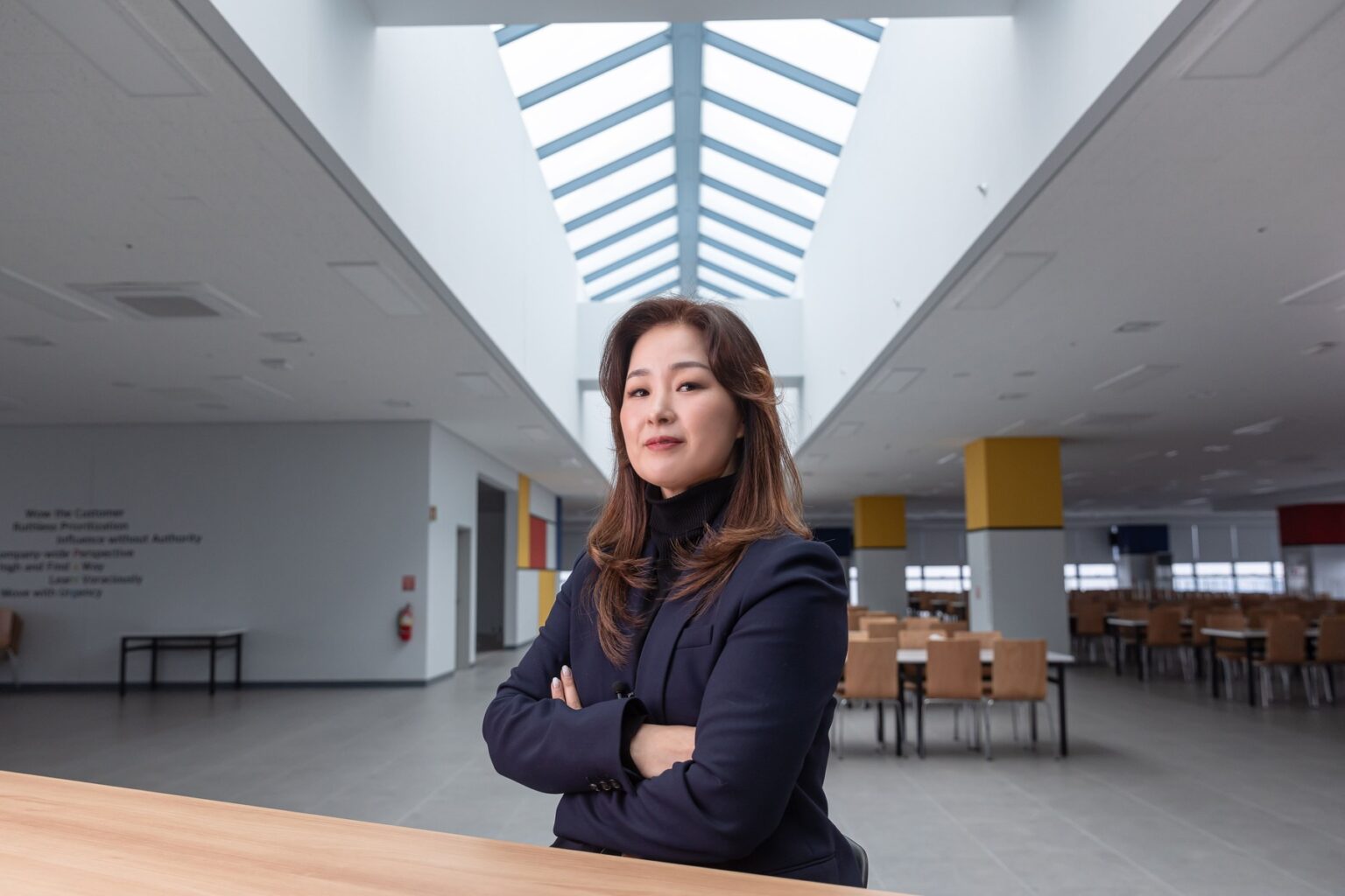 천장과 창문이 있는 방에서 팔짱을 끼고 서 있는 사람