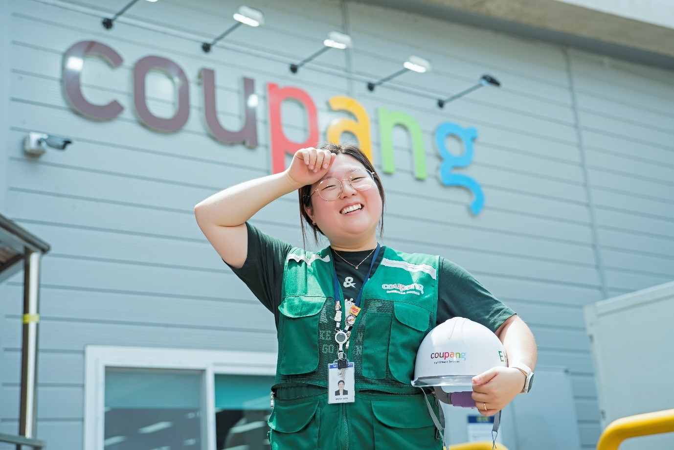 초록색 작업복을 입고 헬멧을 들고 있는 사람