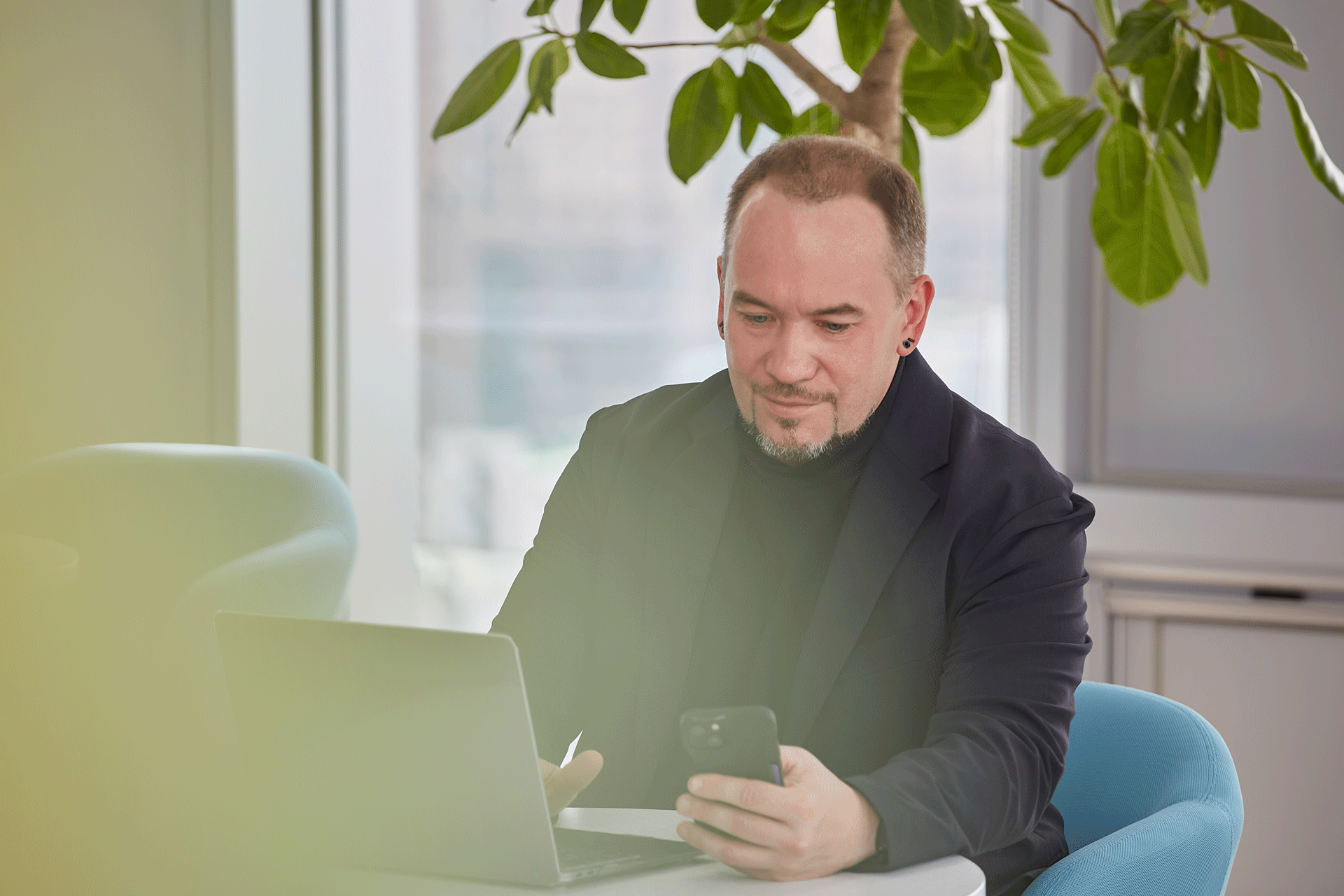 a person sitting at a table with a laptop and a phone