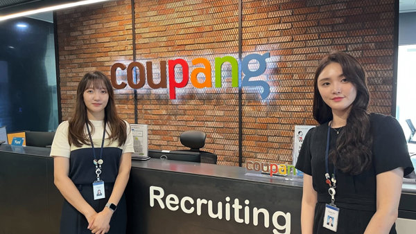 two women standing next to a desk