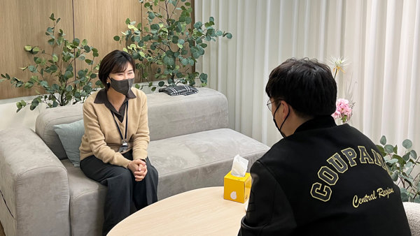 a person sitting on a couch with a person wearing a mask
