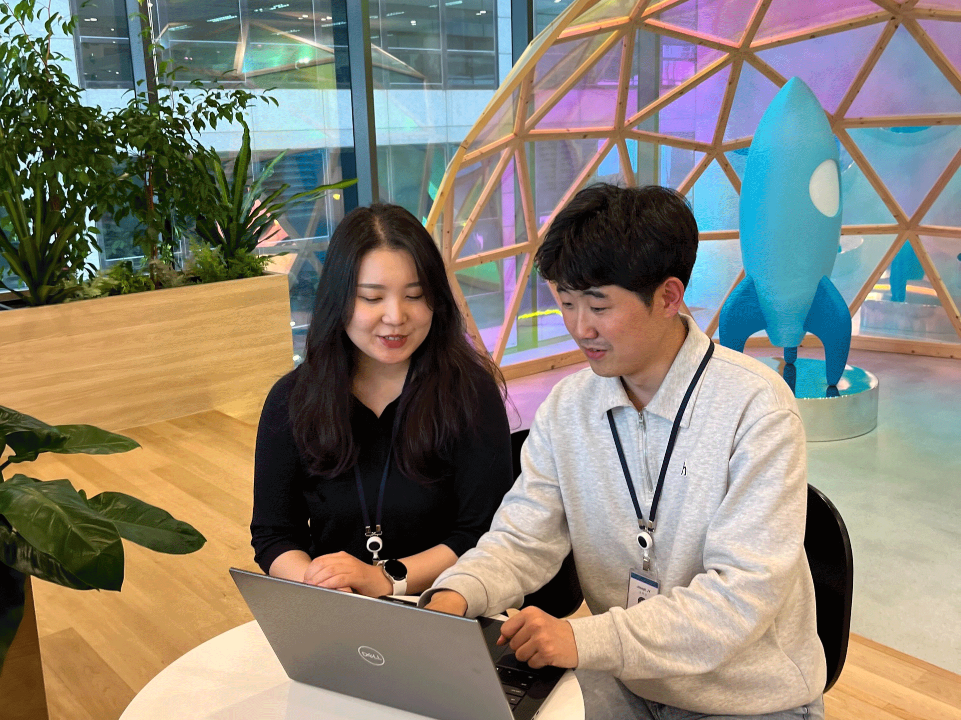 a person and person sitting at a table looking at a laptop