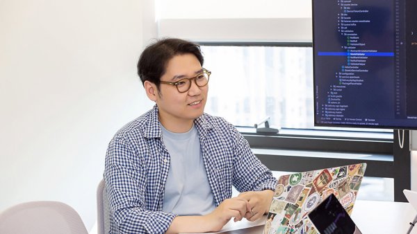 노트북과 컴퓨터가 있는 책상에 앉아 있는 사람