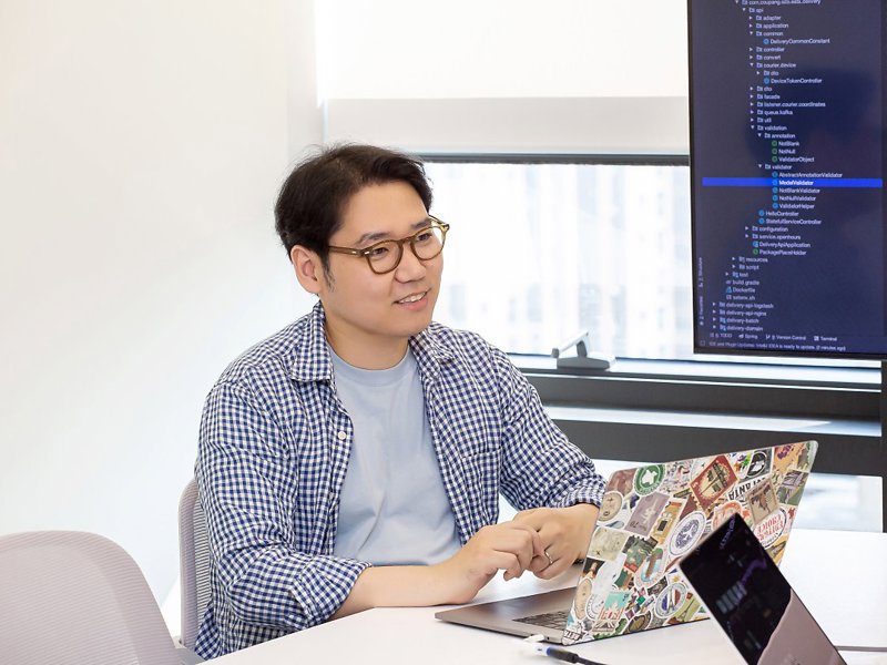 노트북과 컴퓨터가 있는 책상에 앉아 있는 사람