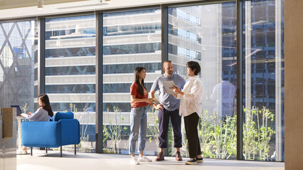 a group of people standing in a room with large windows