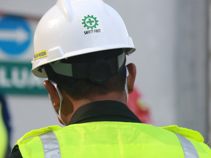 a person wearing a safety vest and a white hard hat