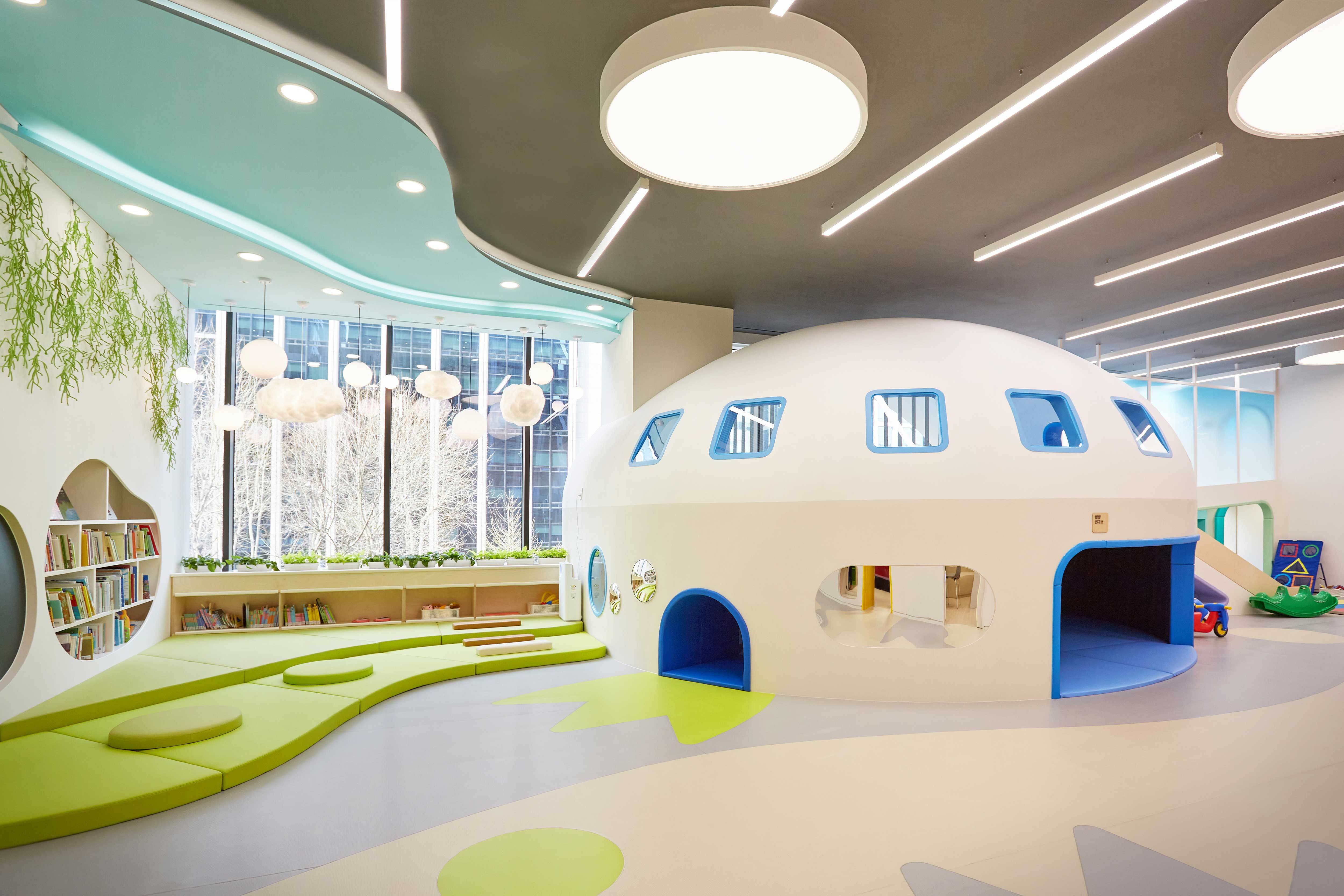 a white dome shaped play area with blue and green seats