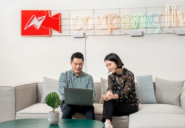a person and person sitting on a couch looking at a laptop