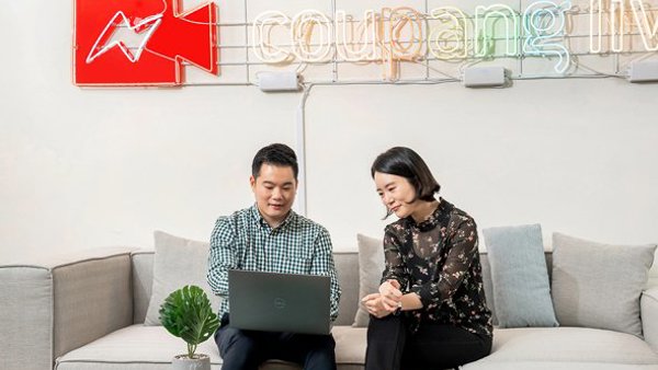 a person and person sitting on a couch looking at a laptop