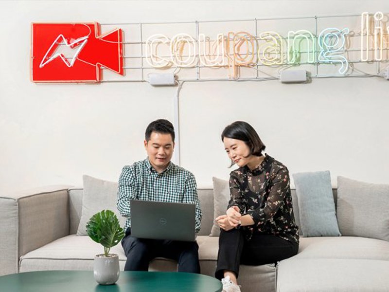 a person and person sitting on a couch looking at a laptop