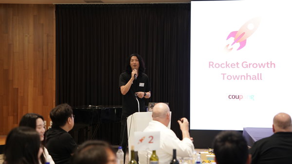 a person speaking into a microphone in front of a group of people