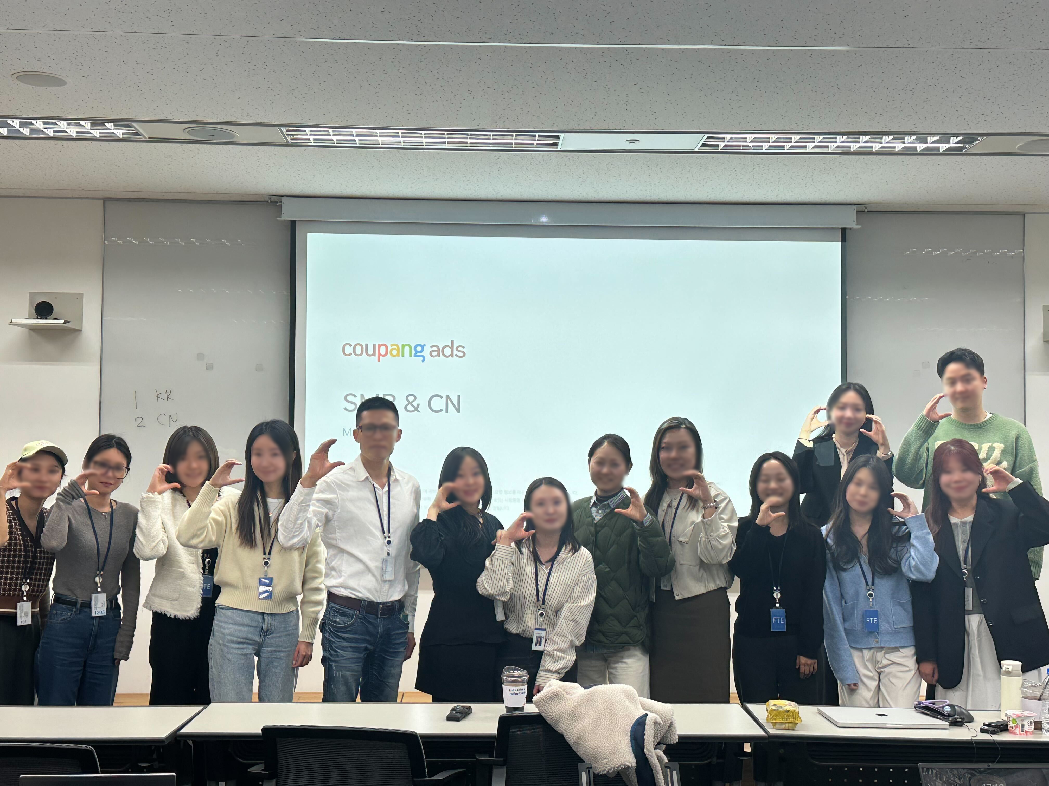 프로젝션 스크린 앞에 서 있는 한 무리의 사람들