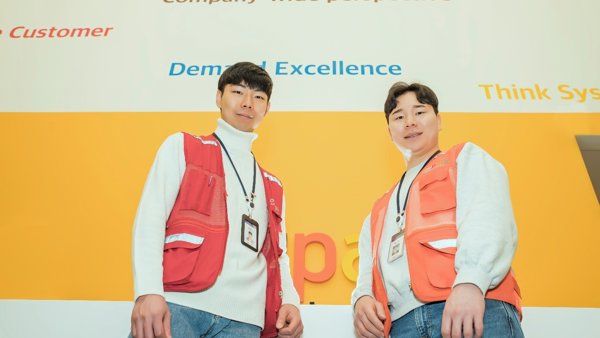 노란 벽 앞에 서 있는 두 남자