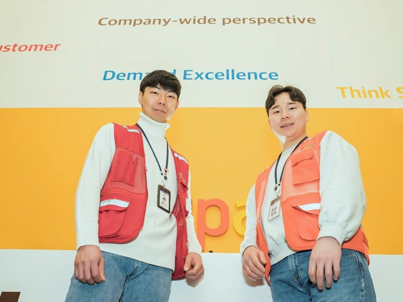 노란 벽 앞에 서 있는 두 남자