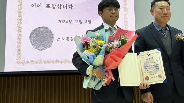 양복을 입은 사람이 꽃과 책을 들고 있습니다