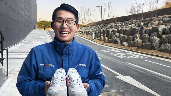 건물 앞에서 신발을 들고 있는 사람