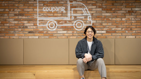 a person sitting on a bench in front of a brick wall