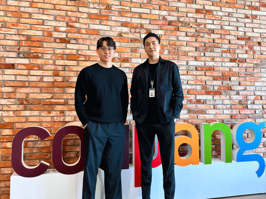 two men standing in front of a brick wall
