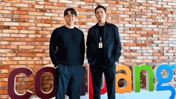 two men standing in front of a brick wall