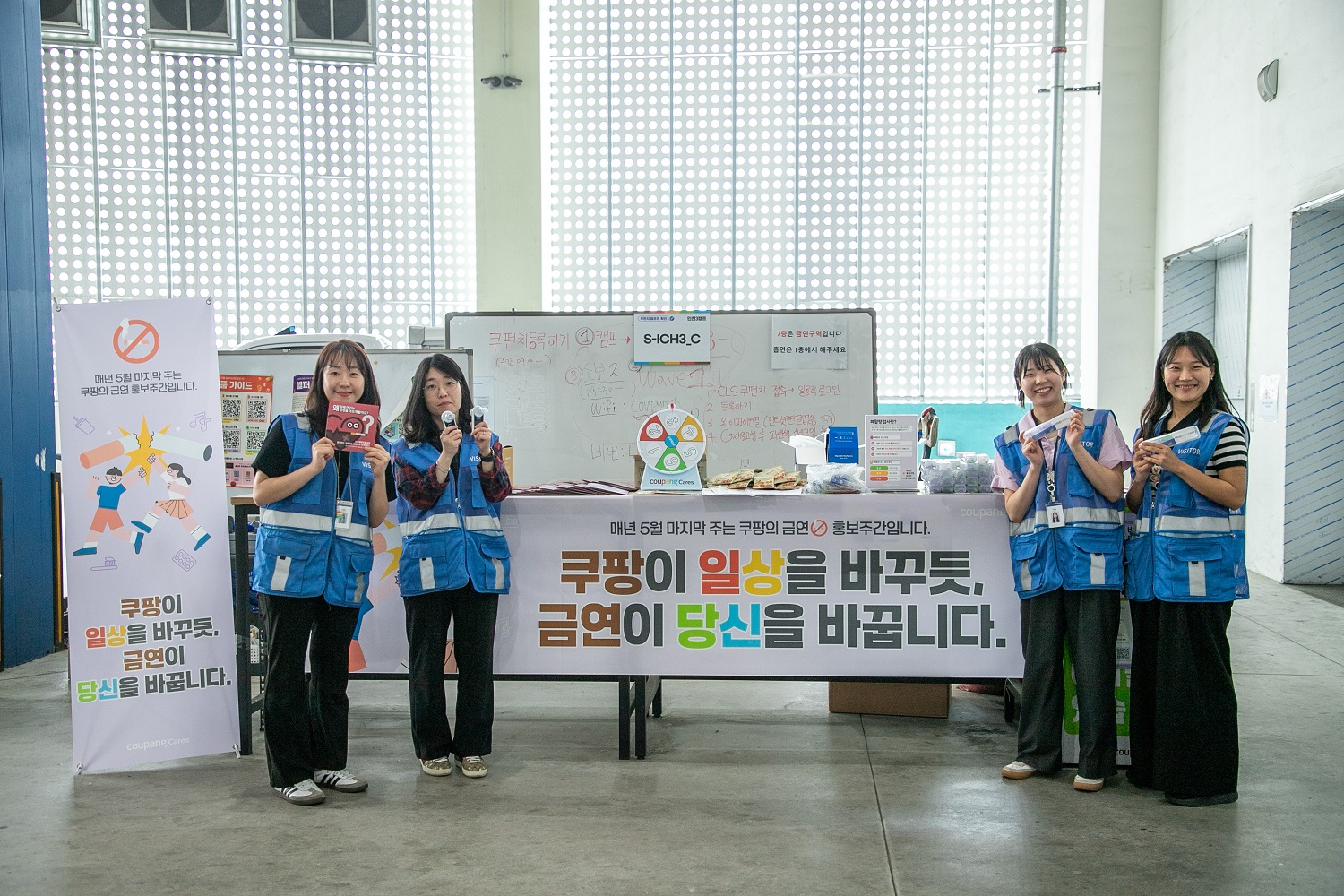 파란 조끼를 입은 한 무리의 여성들이 화이트 보드 앞에 서 있다