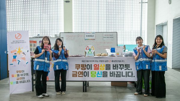 파란 조끼를 입은 한 무리의 여성들이 화이트 보드 앞에 서 있다