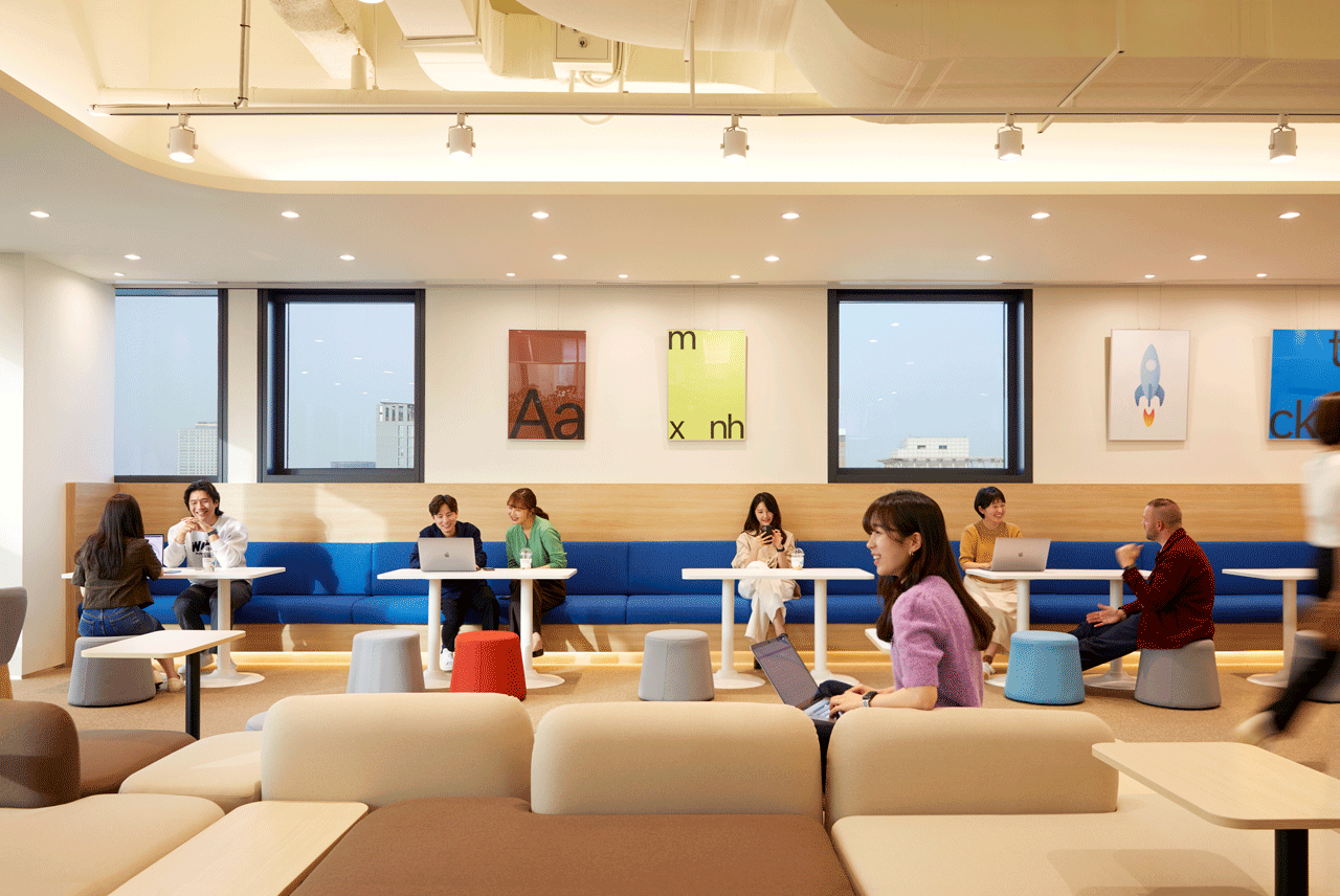 테이블과 의자가 있는 방에 앉아 있는 한 무리의 사람들