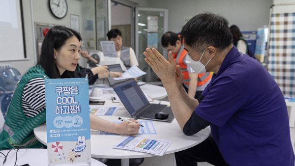 一群人坐在一張桌子旁,手裡拿著一台筆記型電腦和一個標誌
