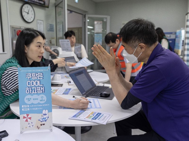 一群人坐在一張桌子旁,手裡拿著一台筆記型電腦和一個標誌