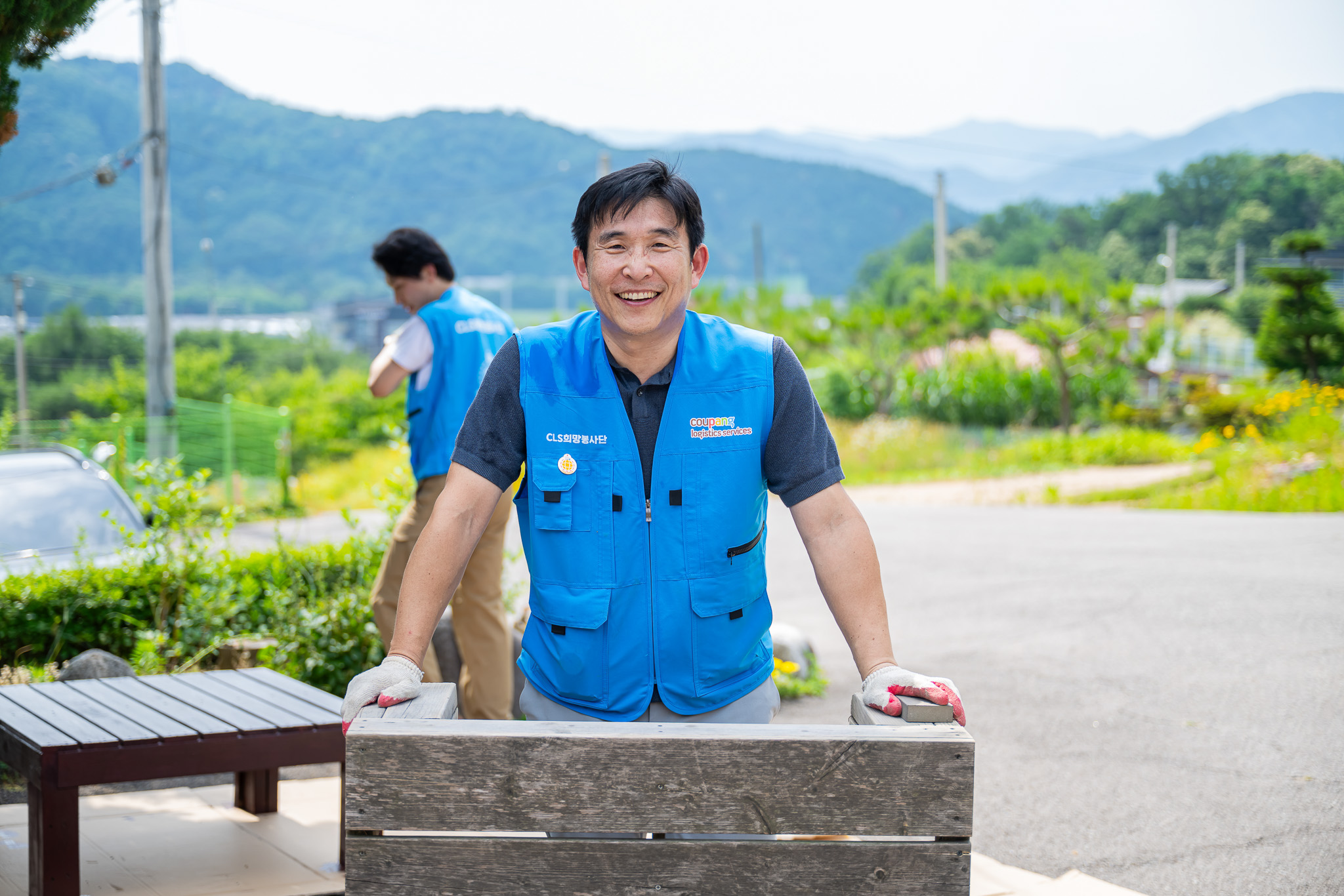 파란 조끼를 입은 사람이 웃고 있다