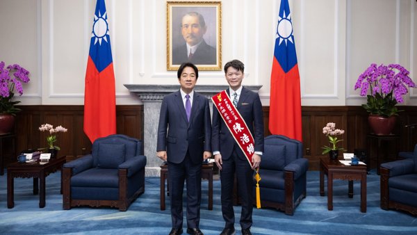 兩個西裝革履的男人站在一個房間里,房間里有旗幟和一張人的照片